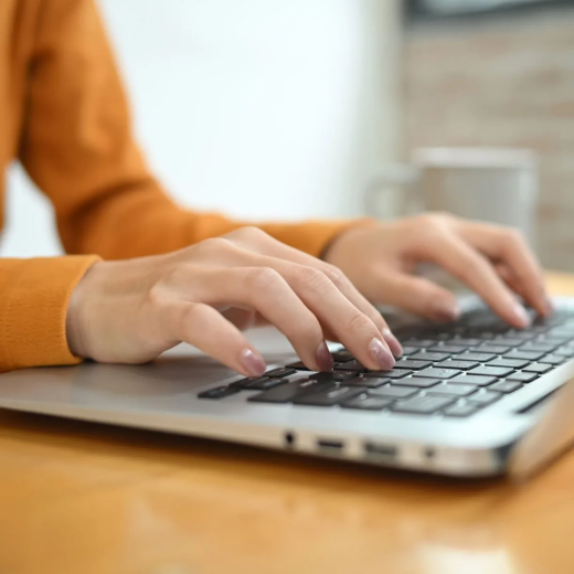 Hands, woman and laptop keyboard at a table