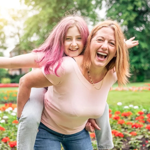 Mother and daughter playing at park and enjoying piggyback ride
