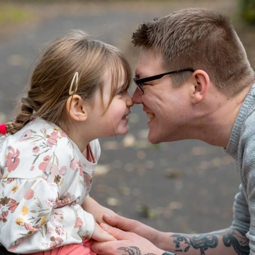 A close up side view of a father and his young daughter having a cute affectionate moment